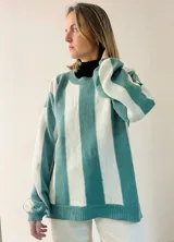 Sweater tejido a rayas horizontales anchas en color celeste y blanco, con sutil brillo. Diseño amplio y cómodo.
