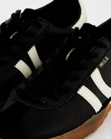 Zapatillas deportivas Coolway Mile de inspiración retro, color negro con detalles en blanco y suela color caramelo. Confeccionadas en nylon y piel auténtica, con lengüeta semitransparente acolchada, cordones bicolor intercambiables y logo "MILE" en oro envejecido.