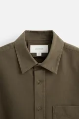 Camisa color crudo de algodón con acabado cepillado, corte relaxed fit, cuello solapa, manga larga con puño abotonado, bolsillo de parche en el pecho, efecto lavado y cierre frontal abotonado.