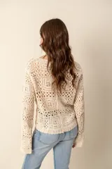 Cardigan color crema tejido al crochet con diseño calado, escote en V y cierre frontal con botones.