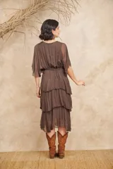 Vestido midi marrón de gasa con volados y mangas cortas tipo kimono. Tiene cintura elastizada y corte evasé. Incluye enagua.