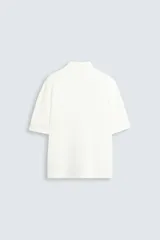 Camisa de manga corta con cuello bowling y calce relajado. Presenta un tejido con textura estructurada y efecto lavado, con cierre frontal de botones al tono.