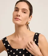 Vestido midi evasê negro con lunares blancos, breteles anchos, escote cuadrado y lastex en la espalda.