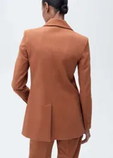Blazer color ladrillo con solapas de muesca, cierre frontal con botón, bolsillo de parche en el pecho y dos bolsillos de parche frontales. Incluye cinturón plateado con forma de flor.