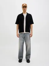 Polo negro de tejido cable knit con fit relajado, cuello tipo polo, manga corta y cierre con botones.