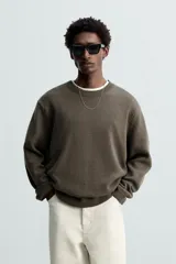 Jersey negro de corte boxy fit, tejido en hilatura con mezcla de algodón y 13% de cashmere. Tiene cuello redondo, manga larga y acabados en rib.