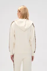 Sweater color crema con capucha y cordones, de tejido de punto, con mangas largas y detalle de franja con estampado animal en mangas y laterales.