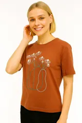 Remera de algodón color ladrillo con estampado de flores en un jarrón. Corte clásico, cuello redondo y mangas cortas.