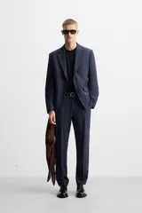 Pantalón de vestir azul marino, de corte slim fit, con bolsillos laterales y traseros de doble vivo con botón. Se ajusta a la cintura con cierre frontal con cremallera y botón.