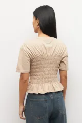 Remera negra de algodón con cuello redondo y mangas cortas. Presenta fruncidos en la cintura.