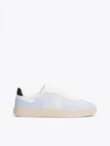 Zapatillas Tommy Hilfiger de cuero sintético color celeste con detalles en blanco y suela color crema. Presentan el logo de la marca bordado en el lateral y detalles distintivos en el talón.