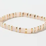 Pulsera elástica con cuentas cilíndricas de color rosa pálido y blanco, separadas por detalles dorados.