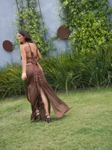 Vestido largo marrón con lunares blancos, escote halter con lazo trenzado al cuello y aberturas en la cintura y en la falda.