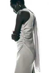 Vestido midi color gris topo, de cuello halter con lazada combinada a tono. Bajo con abertura en espalda. Cierre en espalda con cremallera, abertura y botón.
