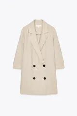 Blazer color beige confeccionada en lino, de corte recto, con cuello solapa, manga tres cuartos con vuelta en el puño, aberturas laterales en el bajo y cierre frontal cruzado con cuatro botones negros.
