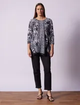 Blusa estampada en blanco y negro con diseño floral, de la marca Ruby Rd. Tiene cuello redondo con apliques de brillos, mangas 3/4 y ruedo asimétrico.