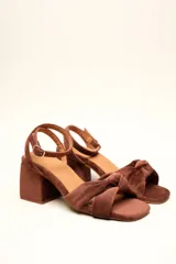 Sandalia de terciopelo verde con taco cuadrado de 7 cm, punta cuadrada y tiras anchas anudadas en el empeine. Cuenta con una tira fina ajustable al tobillo con hebilla dorada.