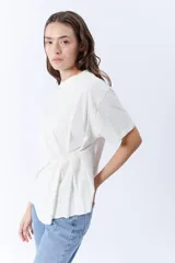 Remera blanca de manga corta con cuello redondo y pinzas laterales que crean un drapeado en la parte delantera.