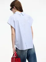 Camisa sin mangas a rayas verticales celestes y blancas, con botones en la parte delantera y trasera, y cuello camisero.