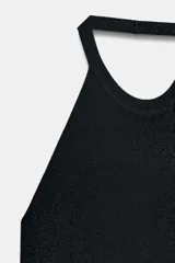 Vestido midi negro, ajustado, con cuello halter y espalda descubierta. El tejido presenta un hilo metalizado que le da un efecto brillante.