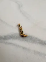 Dije dorado con forma de bota texana con detalles calados en negro.