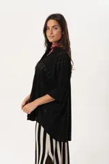 Camisa negra de tejido calado, con escote en V, abotonada y manga 3/4.