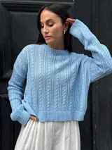 Sweater celeste de tejido calado con diseño en ochos, cuello redondo y mangas largas.