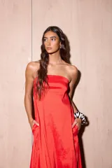 Vestido largo strapless de tafeta color rojo con efecto tornasolado, corte suelto y bolsillos ocultos.