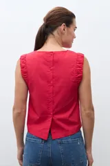 Blusa roja sin mangas, con cuello redondo y sisa drapeada.
