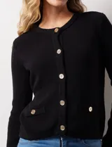 Cardigan tejido negro con escote a la base y abertura central con botones metálicos dorados. Delantera con bolsillos simulados.