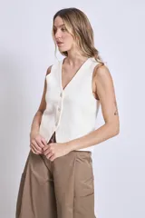 Chaleco de punto sin mangas, color rosado, con escote en V y cierre frontal de tres botones marrones.