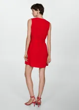 Vestido corto blanco de tejido fluido con cuello pico, cinturón decorativo y bolsillos delanteros.