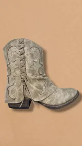 Bota corta de cuero color beige con detalles bordados y cordones frontales.