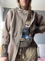 Campera marrón con cierre frontal, cuello alto con capucha y bolsillos laterales.