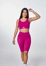 Conjunto deportivo fucsia compuesto por top con logo y calza ciclista de tiro alto.