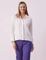 Camisa blanca de gasa, marca Sioni, con cuello con solapa, abertura central con botones y mangas largas con puño y botón.