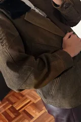 Campera bomber marrón de cuero ovino vintage, con cuello de piel sintética negra desmontable y cierre frontal con cremallera.