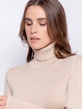Polera de punto color tostado con cuello alto y detalle de botones en las mangas.