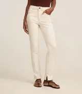 Pantalón slim de jeans color blanco, con cintura mediana, bolsillos delanteros y traseros, cierre con botón y cremallera, y aberturas en el ruedo.