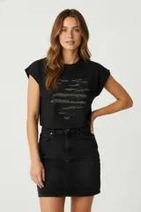 Remera negra de algodón con cuello redondo y mangas cortas. Presenta un estampado abstracto con apliques de strass dorados.