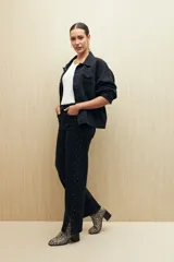 Pantalón de jean negro de corte recto con tachas plateadas en los laterales y tajos en el ruedo.