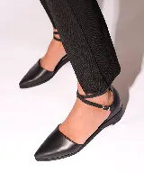 Zapato de cuero negro con punta fina y tiras cruzadas con hebilla al tobillo.