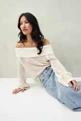 Sweater color crema, tejido de punto calado, con escote off-shoulder y mangas largas acampanadas.