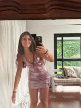 Vestido corto de fiesta color lila metalizado, con escote en V, breteles finos, cut-outs en la cintura y falda ajustada con cordones laterales.