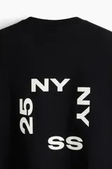Remera negra de corte holgado con estampado blanco en el frente que incluye las letras "NY" y el número "25".