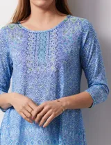 Blusa de modal estampado en tonos celeste, azul y verde, con aplique de brillos en el frente y mangas 3/4.