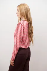 Remera de manga larga con diseño de rayas horizontales en azul y blanco, destacada por un cuello redondo en color bordó con costuras a la vista.