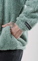 Hoodie verde agua de piel de corderito sintético con calce oversize y cierre central al estilo anorak. La capucha cuenta con cordón ajustable con la palabra Luxo.