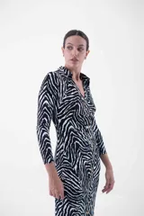 Vestido midi con estampado cebra, corte al cuerpo, cuello camisero y abotonadura frontal.