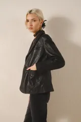 Blazer negro de cuero ovino con proceso de lavado que le da un efecto arrugado. Tiene solapas, bolsillos delanteros y forro interior a tono.